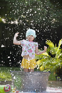 泡浴摄影照片_女孩站在花园的泡泡浴中溅起肥皂泡
