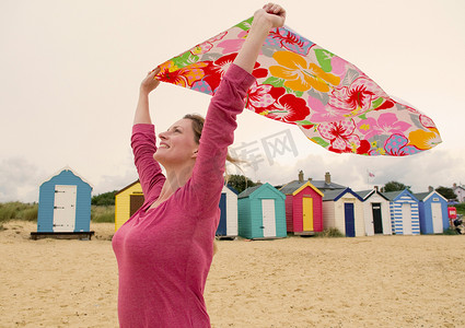 海滩上快乐的女人在风中拿着毛巾