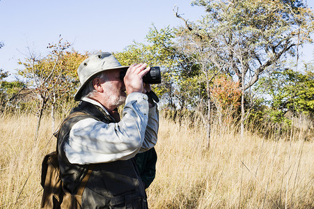 赞比亚卡福国家公园一名老人在狩猎旅行中用望远镜看