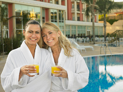 阿利茄汁面摄影照片_两个女人在酒店泳池边喝果汁