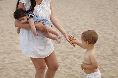 母亲抱着孩子牵着孩子的手