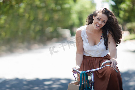 女子骑马摄影照片_一名女子在公园里骑自行车
