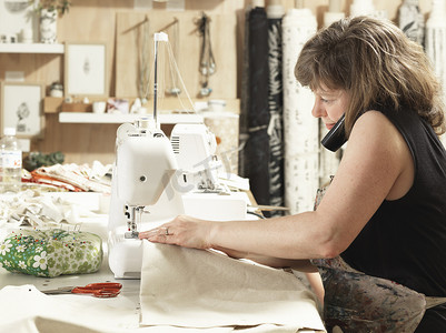 创意背景场摄影照片_妇女在手工印花纺织车间缝纫