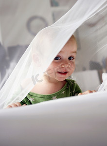 女婴在透明的窗帘里玩耍