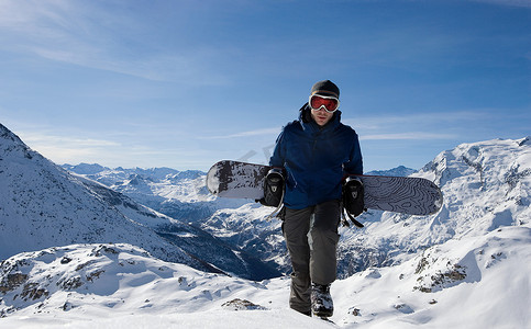冬季雪地靴摄影照片_男子单板滑雪运动员徒步上山