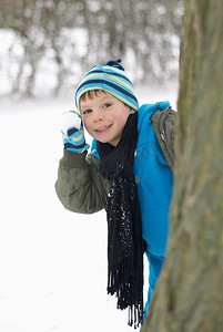 带着雪球躲在树后的男孩