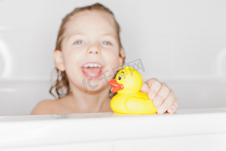 回弹海绵摄影照片_女孩在浴缸里玩橡皮鸭