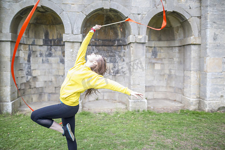 年轻女子练习彩带舞背景是有围墙的拱门