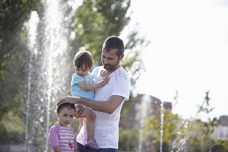 西班牙马德里一名中年男子和两个女儿站在饮水机前