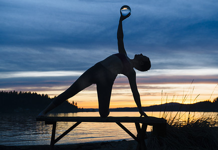 日落时在湖边练瑜伽的女人