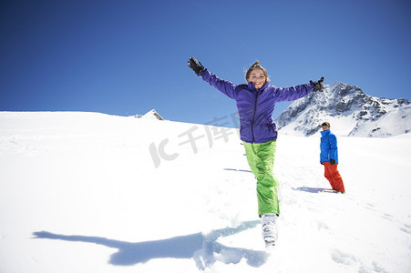 十几岁的女孩在雪地里跳跃张开双臂