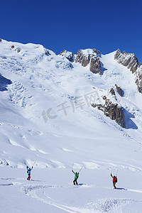 旅游活动中摄影照片_三名成年滑雪者在法国格拉尼亚阿尔卑斯山的勃朗峰上庆祝