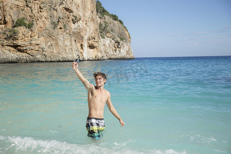意大利撒丁岛奥罗西高尔夫俱乐部用相机微笑举起海洋中的年轻人意大利