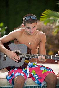 十几岁的男孩在泳池边弹吉他