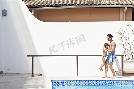爱情阶段摄影照片_父女俩在室外泳池边父亲抱着女儿