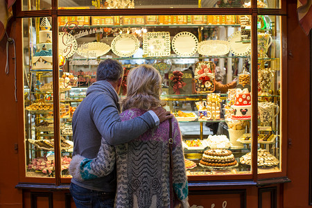 西班牙马略卡岛蛋糕店橱窗里浪漫的成熟夫妇的背影