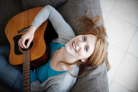 坐在沙发上弹吉他的快乐女孩