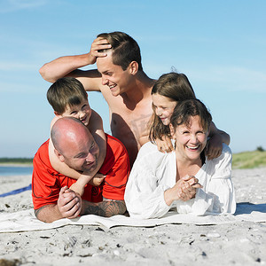 五十肩摄影照片_一家人一起躺在沙滩毛巾上