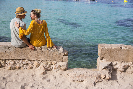 西班牙马略卡岛一对夫妇坐在海边的墙上
