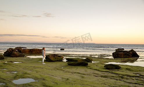 西班牙特拉法尔加角一名女子在岩石海滩上观看日落