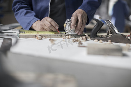 木匠在车间工作台上测量木材的手