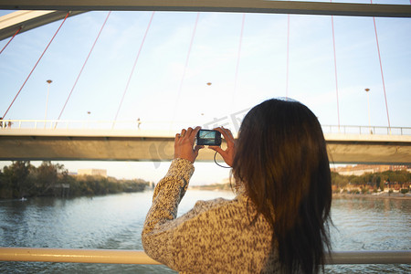 印度国旗摄影照片_西班牙塞维利亚成年女游客在瓜达尔奇维尔河用数码相机拍摄