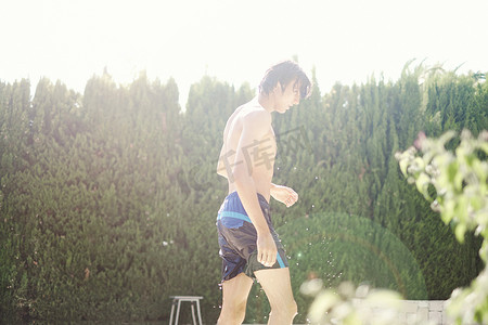一名穿着泳裤的年轻男子在泳池边浑身湿透