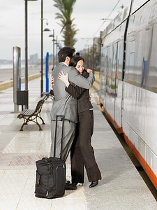 西装革履的情侣在电车站拥抱