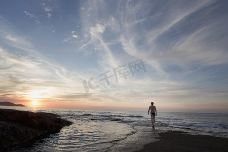 日落时分法国科西嘉岛卡尔维海滩上成熟男子的后部剪影