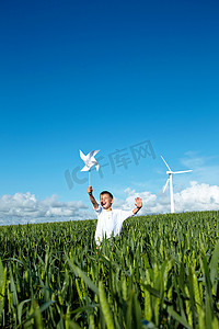 男孩带着风力涡轮机在田野里奔跑