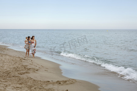 一名怀有身孕的妇女抱着一个蹒跚学步的孩子沿着岸边走着