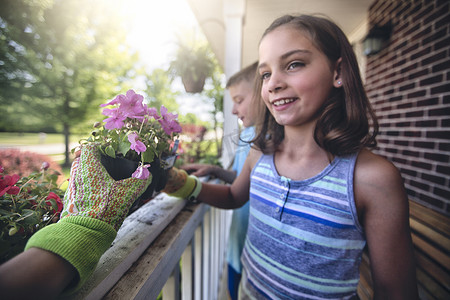 保龄球手套摄影照片_手戴园艺手套将植物交给男孩和女孩