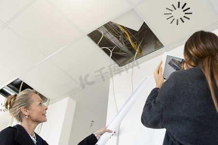 数字18设计摄影照片_女商人在新办公室使用数字平板电脑拍摄天花板
