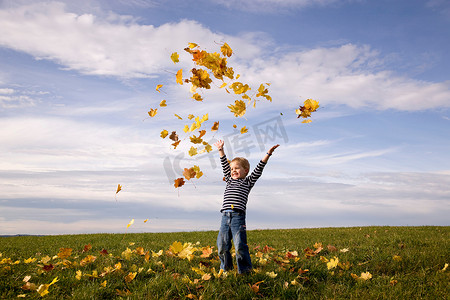 男孩把树叶扔向空中