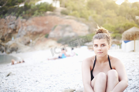 十几岁的女孩抱着膝盖坐在海滩上西班牙