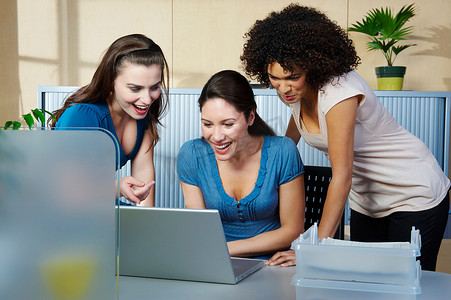 办公协作办公摄影照片_一群年轻女性在办公桌前拿着笔记本电脑
