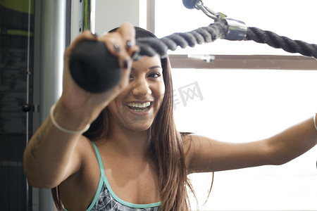 健身房里的女性正在使用健身器微笑着看着相机