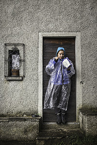 部队保密摄影照片_戴着雨衣的年轻女子站在门口科莫湖意大利