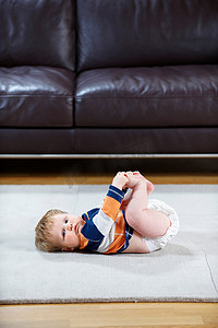 8个月大的婴儿穿着尿布躺在地毯上