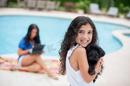 微笑的女孩抱着小狗在泳池边