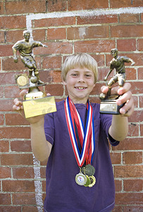 拿着奖牌和奖杯的儿童足球运动员