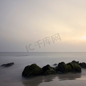 梦幻神秘的背景摄影照片_风平浪静的大海里的岩石
