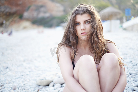 西班牙贾韦亚海滩上留着棕色长发的十几岁女孩抱着膝盖