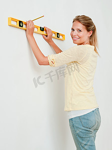 纯色装修摄影照片_年轻女子在墙上使用精神水平仪