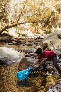 美国加利福尼亚州红杉国家公园矿泉王年轻的男性徒步旅行者带着塑料袋在河里钓鱼