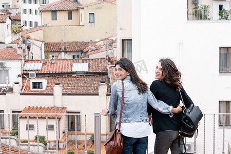 意大利托斯卡纳佛罗伦萨女同性恋夫妇站在屋顶露台上背对着镜头微笑