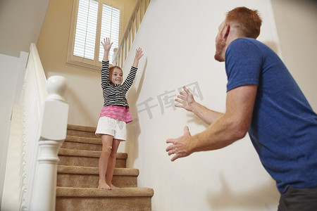 家里的门摄影照片_女孩准备在家里的楼梯上跳进父亲的怀抱