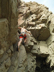 岩面摄影照片_攀岩者攀登陡峭的岩面