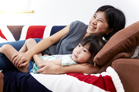 中国国旗摄影照片_年轻的中国母女俩在家一起躺在沙发上看电视