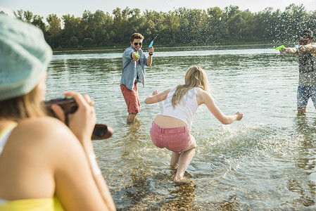 男性玩游戏摄影照片_朋友们在湖里玩水枪